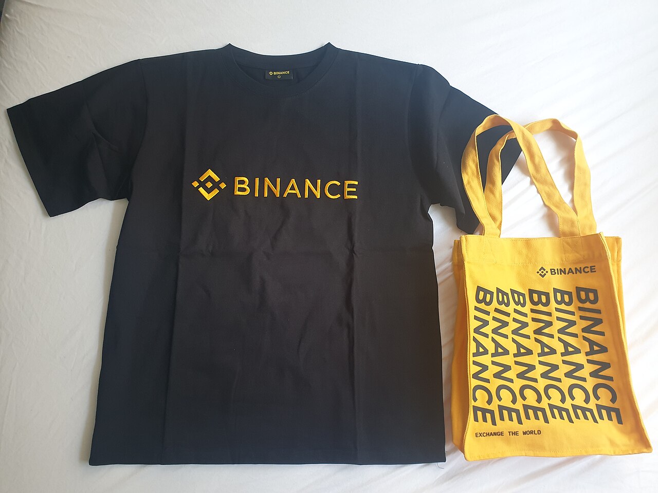 Black Binance t-shirt and yellow Binance tote bag with the exchange logo